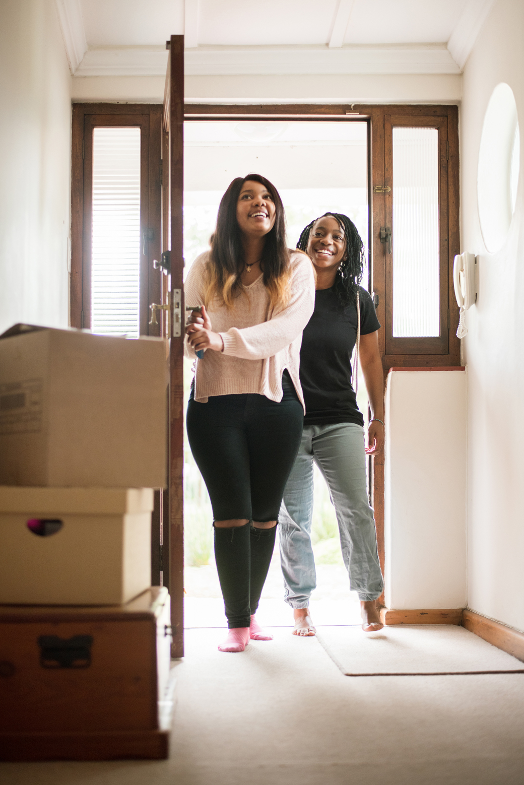 Shot of two young women entering their new home from the main door